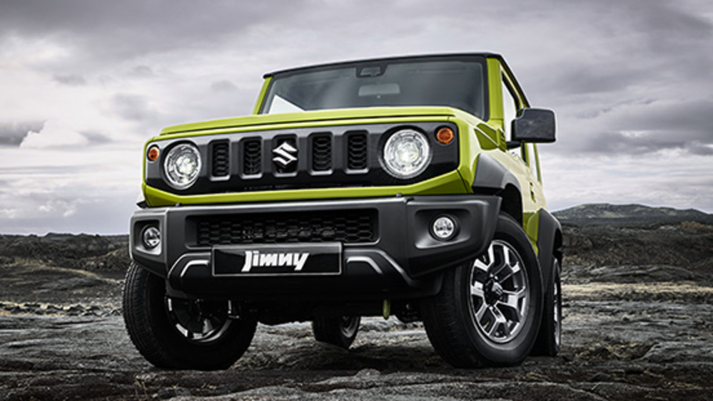 A light yellowish-green Suzuki Jimny stopped in a rocky area.